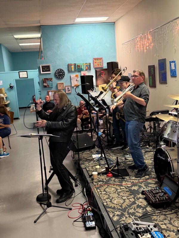 Ryan Evans singing with the trombone, saxophone and trumpet players behind him